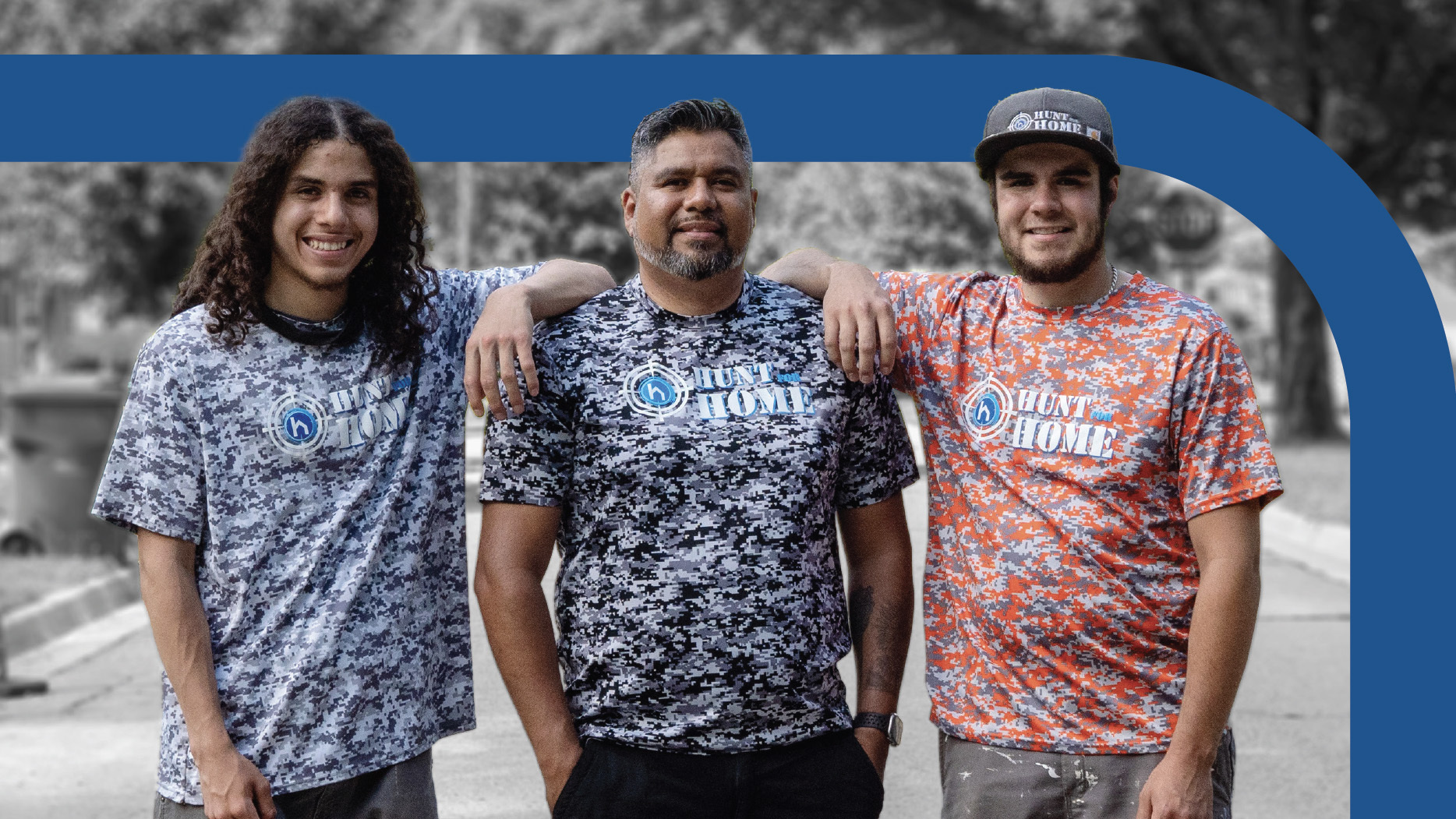 Three gentleman wearing Hunt for Home shirts standing together in street
