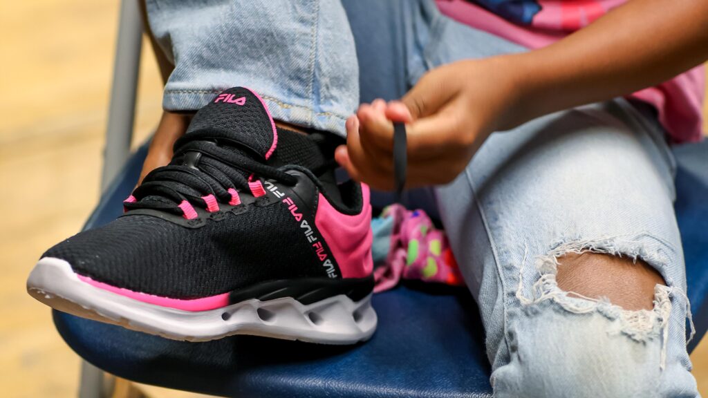 image of child putting on pink and black sneaker