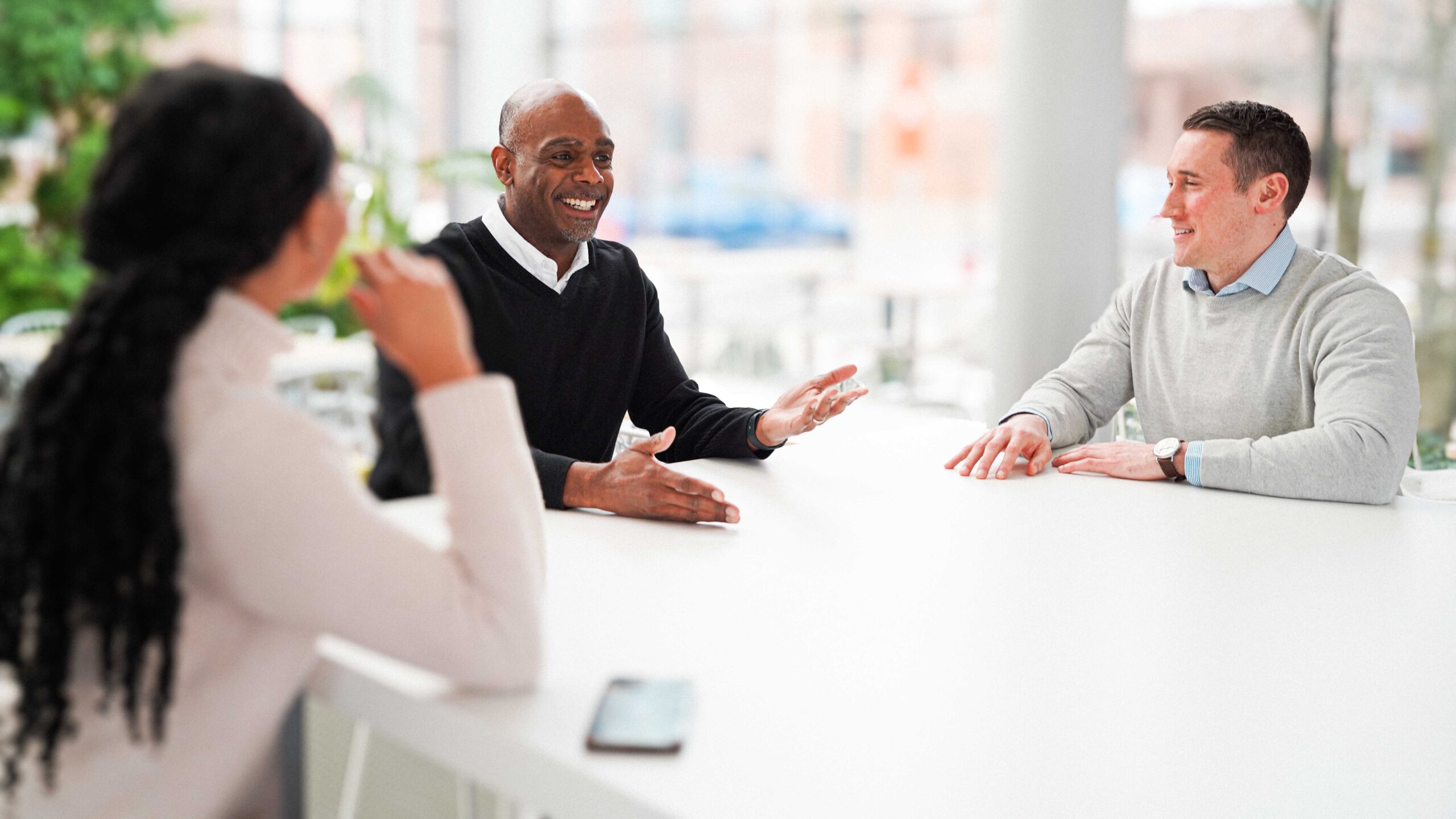 Image of Chief Investment Officer, Josh Sledge talking with colleagues around a square table.