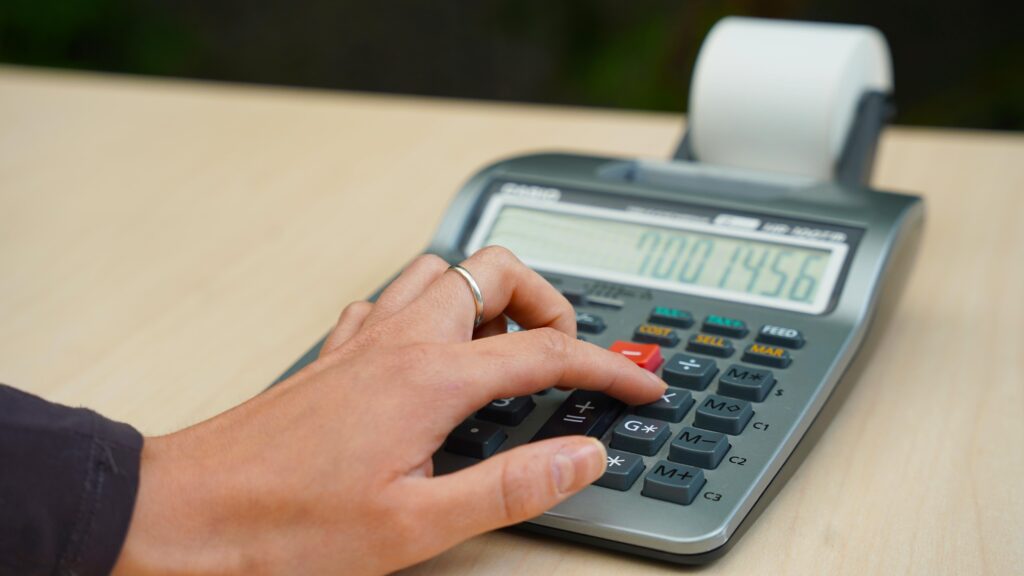 Image of woman's hand pressing the multiply button on a calculator