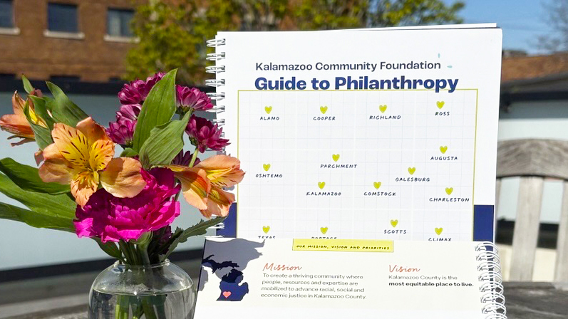 A picture of our Guide to Philanthropy outside next to brightly colored flowers
