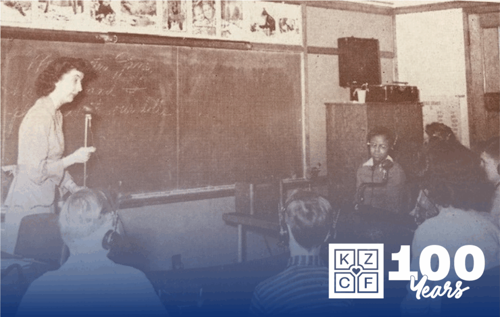 Kalamazoo Public Schools photo from 1930's, showing a teacher in front of a blackboard talking to students.