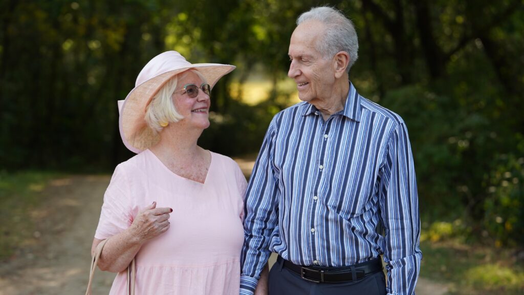 A man and a woman looking at each other lovingly in a wooded setting.