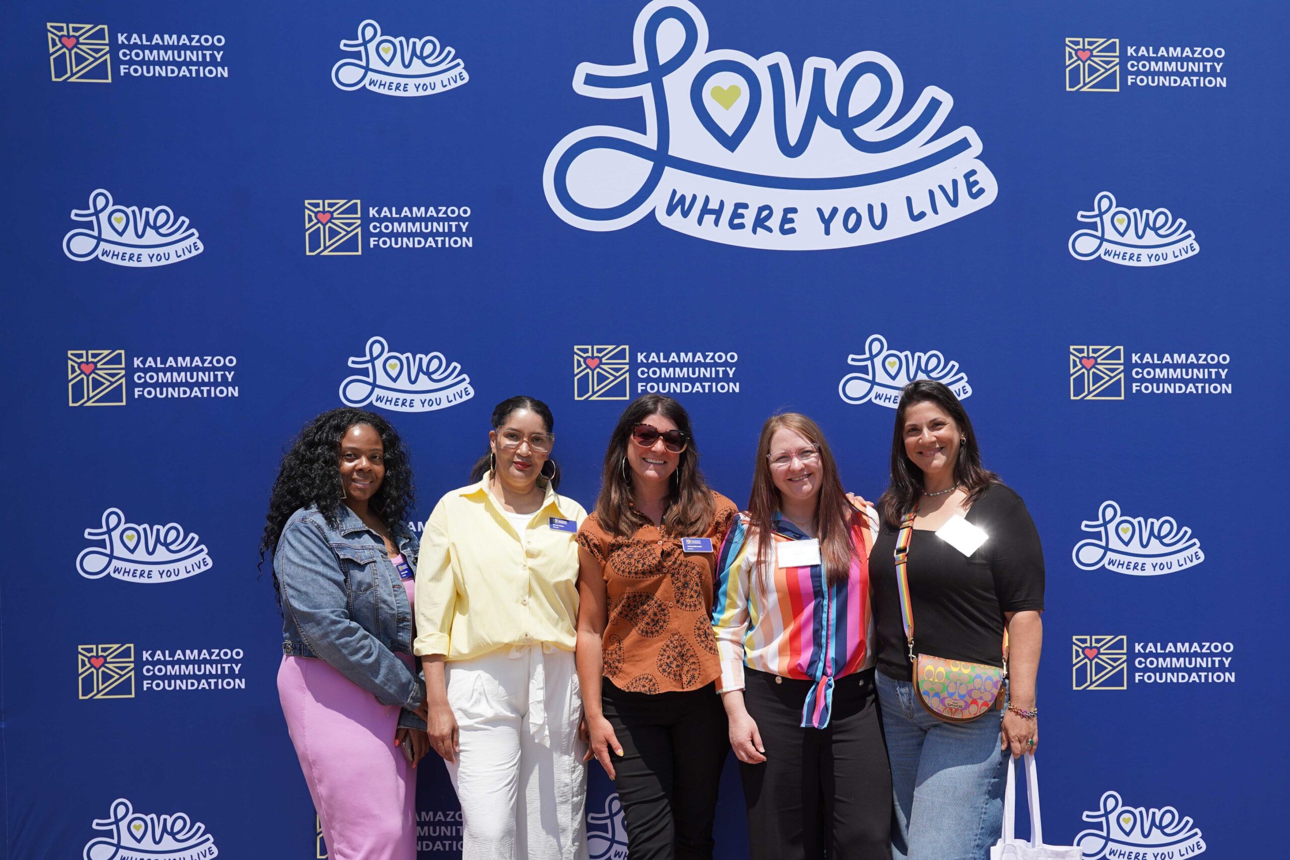 KZCF Staff and Bus Tour attendees in front of our blue Love Where You Live backdrop